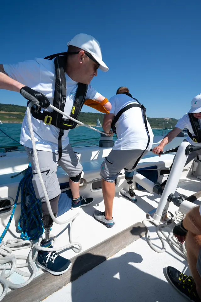 Simon hauling a rope on deck during a Stride Forward sailing challenge, with his prosthetic leg visible